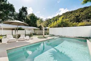 une piscine avec deux chaises et un parasol dans l'établissement Nala Cottage at Patonga, à Patonga Beach