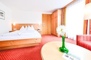 pokój hotelowy z łóżkiem i wazą z kwiatem w obiekcie Hotel-Pension Hoferhaus w mieście Neukirchen am Großvenediger