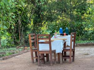 a table with two wooden chairs and a white table cloth at Kibale Tented Camp in Kibale Forest National Park