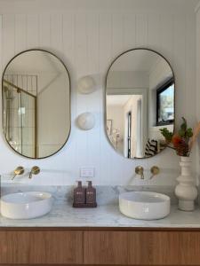 deux lavabos dans une salle de bain avec deux miroirs dans l'établissement PISTE LUXURY CHALET - THE GRANDE - Oaks Lake Crackenback Resort, à Crackenback