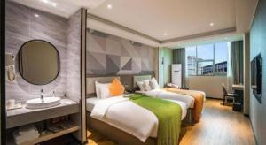 吉安市にあるBorrman Hotel Ji'an Railway Station Jinggangshan Universityのベッド2台と洗面台があるホテルの部屋