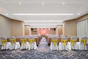a room with rows of tables and yellow chairs at Echeng Hotel Enshi Minzu Road in Enshi