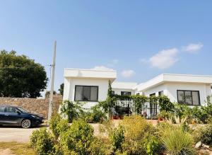 une maison blanche avec une voiture garée devant elle dans l'établissement Pearl Pride Villa Udaipur, à Udaipur