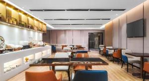 a restaurant with tables and chairs and a flat screen tv at Echarm Hotel Nanjing Expo Center Olympic East Metro Station in Nanjing