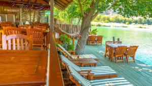 a deck with tables and chairs and a tree and water at Dalyan Pension in Dalyan