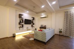 斋浦尔Royal Saket的客厅里有一张沙发和一台电视