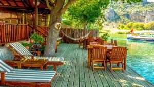 a wooden deck with tables and chairs next to the water at Dalyan Pension in Dalyan