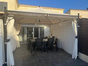 a patio with a table and chairs under a canopy at Maisonnette privé bord de mer Poggio mezzana in Poggio-Mezzana