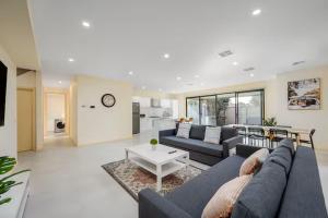 a living room with a blue couch and a table at Fantastic Large Family Home, 6 Mins to Melbourne Airport in Melbourne