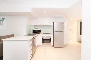 a kitchen with white cabinets and a refrigerator at Hotel Chino in Brisbane
