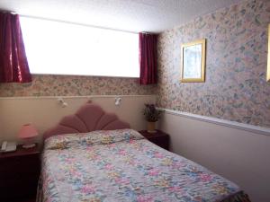 una camera da letto con un letto con carta da parati floreale e una finestra di Old Lamb Hotel a Reading