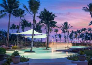 a resort pool with palm trees at dusk at Shangri-La Hambantota in Hambantota