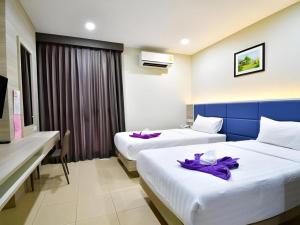two beds in a hotel room with purple robes on them at Sattahip 9 Boutique Hotel in Sattahip