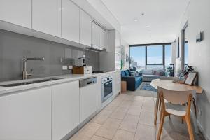 Una cocina con gabinetes blancos y una mesa. en Oasis Retreat on Level 71 in Skytower, en Brisbane