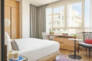a bedroom with a bed and a desk and a window at Hyatt Centric Gran Via Madrid in Madrid