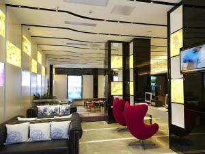 a living room with a couch and chairs and a television at LAVANDE Hotel Dalian Huanan Square North Railway Station in Dalian