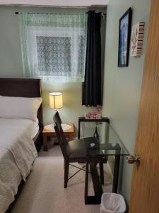 a bedroom with a bed and a desk and a glass table at Singleton Room in a pet and smoke-free home in Winnipeg