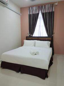 a bedroom with a large white bed with a window at Ummi Guesthouse in Dungun