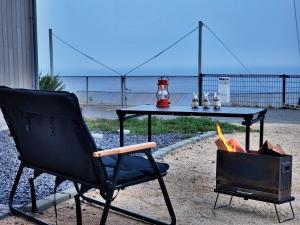 a black chair sitting next to a table with a stove at 「淡路島一棟貸宿　野うさぎ 」高台から海を望む貸別荘！2023年新築離れの素泊まり in Noda