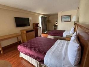 a hotel room with two beds and a flat screen tv at Grand Park Inn in Baldwin Park