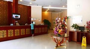 a man standing at a counter in a hotel lobby at GreenTree Inn Kunshan Shimao Plaza Business Hotel in Penglang