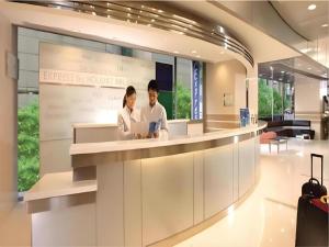 two people standing at a counter in a lobby at Holiday Inn Express Jinan Exhibition Center By IHG in Jinan