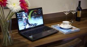 a laptop computer sitting on a wooden table with a vase of flowers at Hanyong Hotel Shenzhen International Exhibition Center in Fenghuangwei