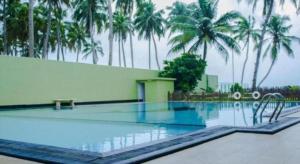 a swimming pool with palm trees in the background at Hotel Villa Viana in Horagolla +16 photos