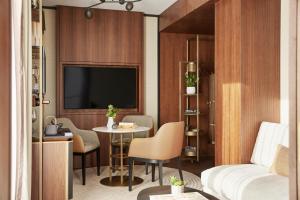 Cette chambre d'hôtel dispose d'une télévision, d'une table et de chaises. dans l'établissement Thompson Madrid, by Hyatt, à Madrid