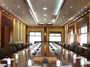 Una gran sala de conferencias con una mesa larga y sillas. en Wutaishan Wufeng Hotel, en Wutai