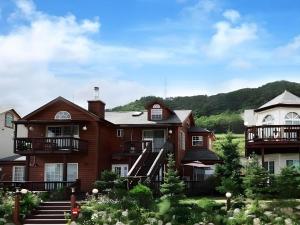 une grande maison avec une montagne en arrière-plan dans l'établissement Daegwalnyeong Sky Keeper Pension, à Pyeongchang