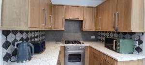 a kitchen with wooden cabinets and a stove top oven at Cheltenham town centre with parking space in Cheltenham +15 photos