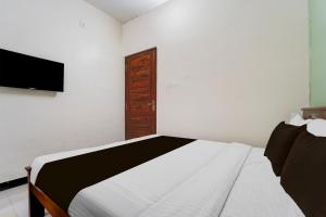 Un dormitorio con una cama y un televisor de pantalla plana. en Super Hotel O Central Zone Vishwanathapuram Formerly Green Nest, en Coimbatore
