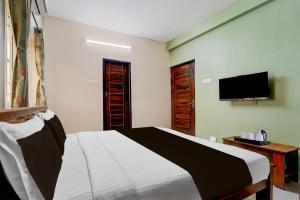 Un dormitorio con una cama y un televisor de pantalla plana. en Super Hotel O Central Zone Vishwanathapuram Formerly Green Nest, en Coimbatore 20 fotos más