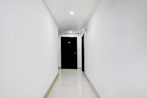 an empty corridor with a black door and white walls at Townhouse Oak Ballygunge Formerly Hotel Lovelock in Ballygunge