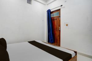 a bedroom with a bed with a door and a window at Super Hotel O Prayagraj Sangam Railway Junction Formerly Veni Madhv Inn in Dārāganj +21 photos