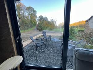 Elle offre une vue sur une terrasse dotée de chaises et d'une table. dans l'établissement Gîte du Moulin, à Commer