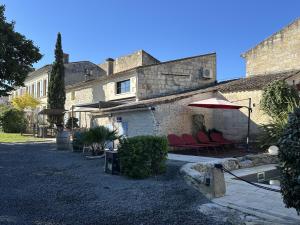 een huis met rode stoelen en een parasol bij Maison JEROBOAM in Saint-Estèphe