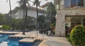 a building with a swimming pool next to a house at Jelita Bandara Hotel Airport in Ulin