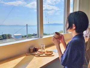 a young girl holding a coffee cup in front of a table with food at 「淡路島一棟貸宿　野うさぎ 」高台から海を望む貸別荘！2023年新築離れの素泊まり in Noda