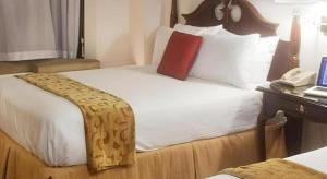 a bed in a hotel room with a phone on a desk at Hilgard House Westwood Village in Los Angeles