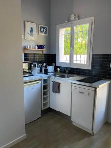 a kitchen with white counters and a sink and a window at Studio indépendant avec terrasse dans propriété campagne Aixoise in Aix-en-Provence