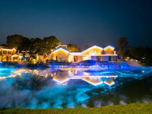 a house with a pool of water at night at Chaoyangli Folk Resort Hotel in Zhaoqing