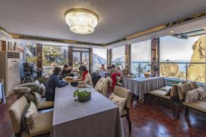 a restaurant with people sitting at tables in a room with large windows at Huangshan Yupinglou Hotel in Beihaibinguan