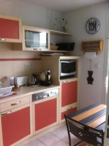 a kitchen with red cabinets and a microwave at La Paloma in Aigues-Mortes