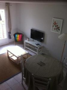 a living room with a table and a television at La Paloma in Aigues-Mortes