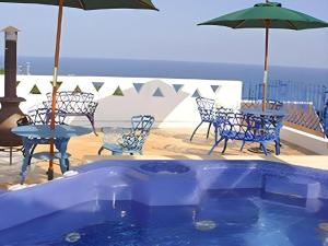 a pool with chairs and tables and an umbrella at Arabian Art Hotel & Gallery in Kawaguchi
