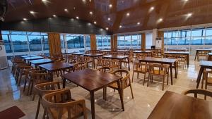 a restaurant with wooden tables and chairs and windows at Berkat Surya Dewa Guest House in Benuaanyar