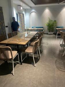 Un hombre de pie en una habitación con mesas y sillas. en Precesion Palace Suites Near Delhi Airport, en Nueva Delhi