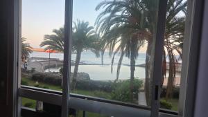 ein Fenster mit Blick auf das Meer und die Palmen in der Unterkunft La paz del Mar en Arguineguin in Arguineguín